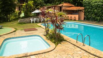 A swimming pool with stone tiles, a bar area, and a small outdoor seating area with chairs and a table.