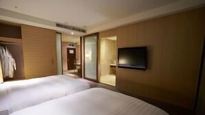 A hotel room with two beds, a TV, and a wardrobe.