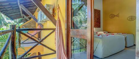 Una habitación con dos camas, un ventanal con vista a palmeras y una hamaca afuera.