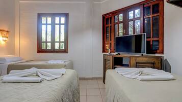 Habitación de hotel con dos camas, un televisor y ventana con vista a follaje.
