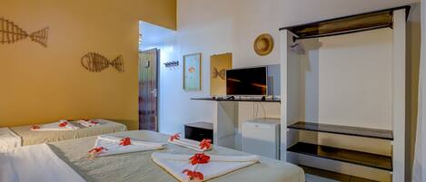 A hotel room with two beds, a TV, a shelf, and artwork on the walls.