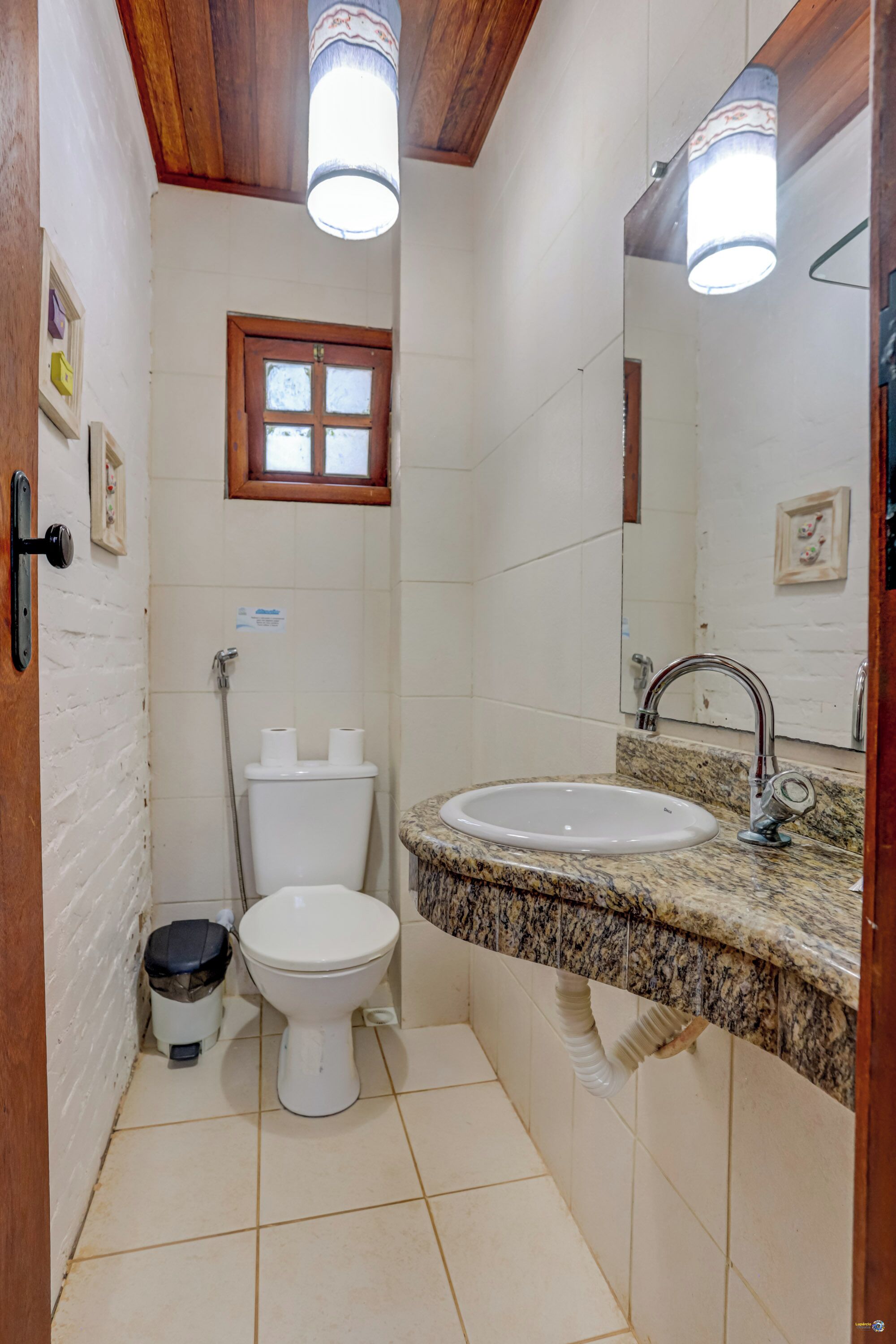A compact bathroom with a white toilet, a sink with a granite countertop, and a mirror above the sink.