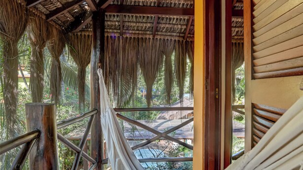A wooden deck with a hammock, wooden railings, and a thatched roof. - Pousada Villa N'Kara (Itacaré)