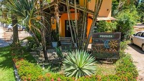 A hotel entrance with a sign reading "POUSADA NIKARA" surrounded by tropical plants and a palm tree. - Pousada Villa N'Kara (Itacaré)