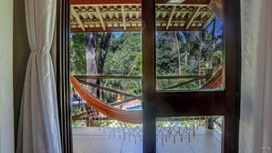 A view from a window with a hammock, wooden ceiling, and lush greenery outside. - Pousada Villa N'Kara (Itacaré)