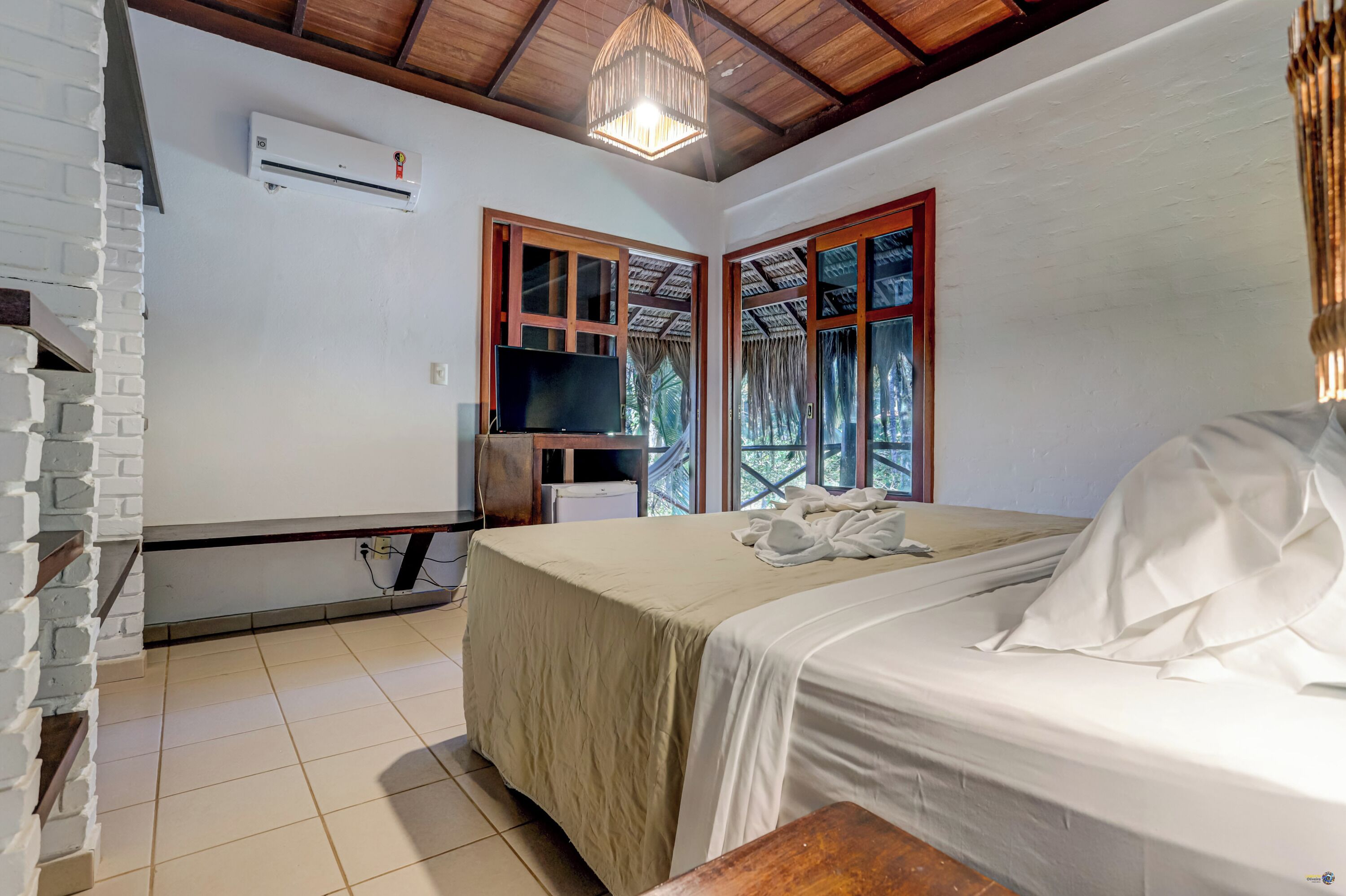 A bedroom with a bed, a television, and a window with curtains.