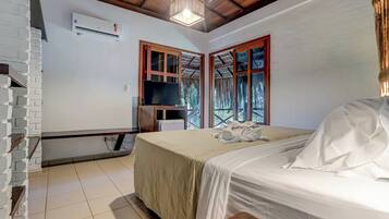 A bedroom with a bed, a television, and a window with curtains.