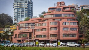 Un hotel con una arquitectura curva distintiva, varios balcones y una terraza en la azotea.