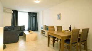 A living room with a sofa, a coffee table, a TV, and a dining table with chairs. - Sunset Kosharitsa (KOSHARITSA)