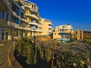 A modern hotel with multiple balconies, a swimming pool, and landscaped gardens. - Sunset Kosharitsa (KOSHARITSA)
