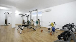 A gym with various exercise equipment including a bench press, weight racks, and free weights. - Sunset Kosharitsa (KOSHARITSA)