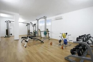A gym with various exercise equipment including a bench press, weight racks, and free weights. - Sunset Kosharitsa (KOSHARITSA)