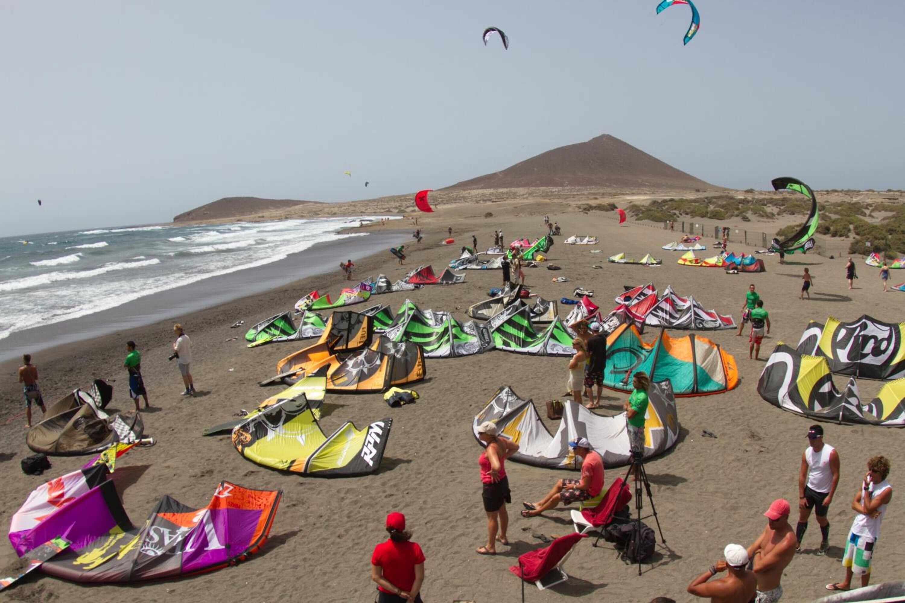 A beach with numerous colorful kites and tents, indicating a kite-flying event.