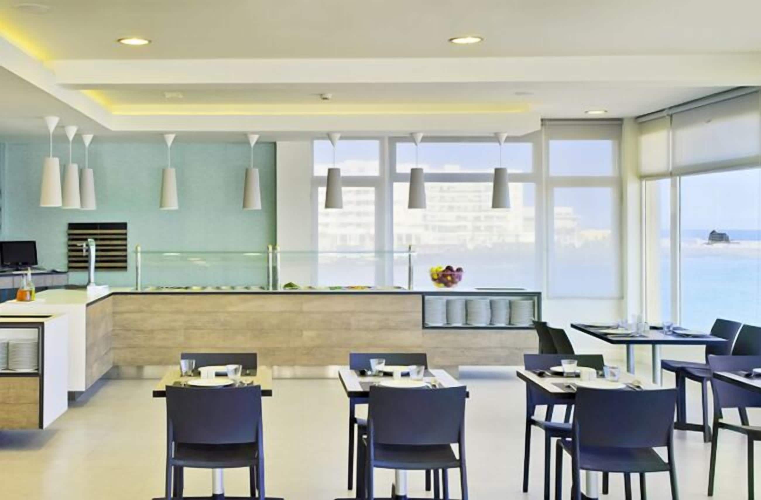 Um restaurante moderno com balcão central, mesas e cadeiras para refeições.