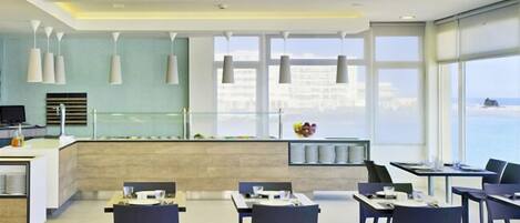 Um restaurante moderno com balcão central, mesas e cadeiras para refeições.