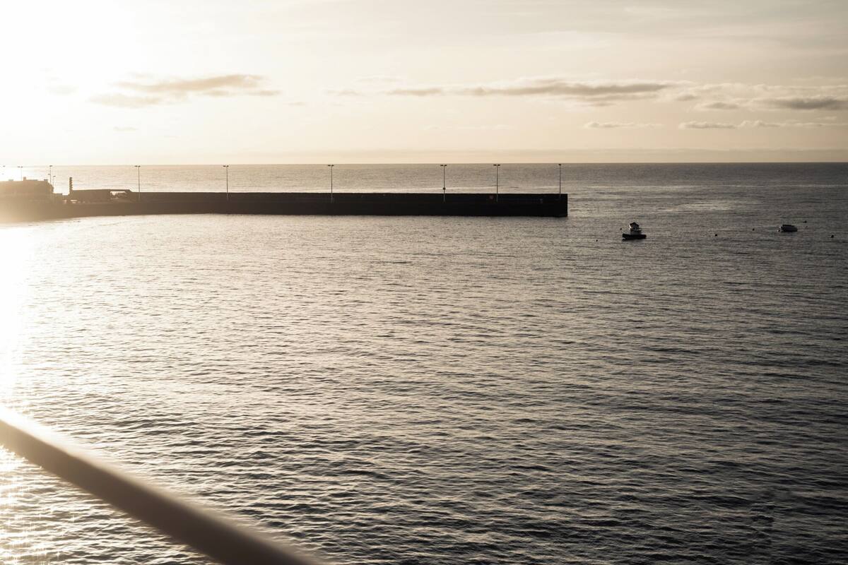 Ruhiges Meer mit einer sich ins Wasser reckenden Mole.