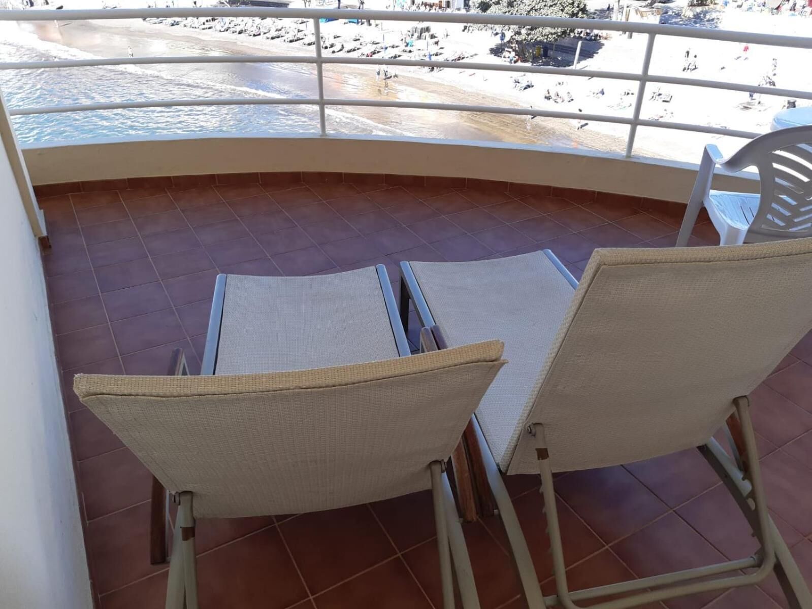 Un balcon avec deux fauteuils en osier et une vue sur la plage.