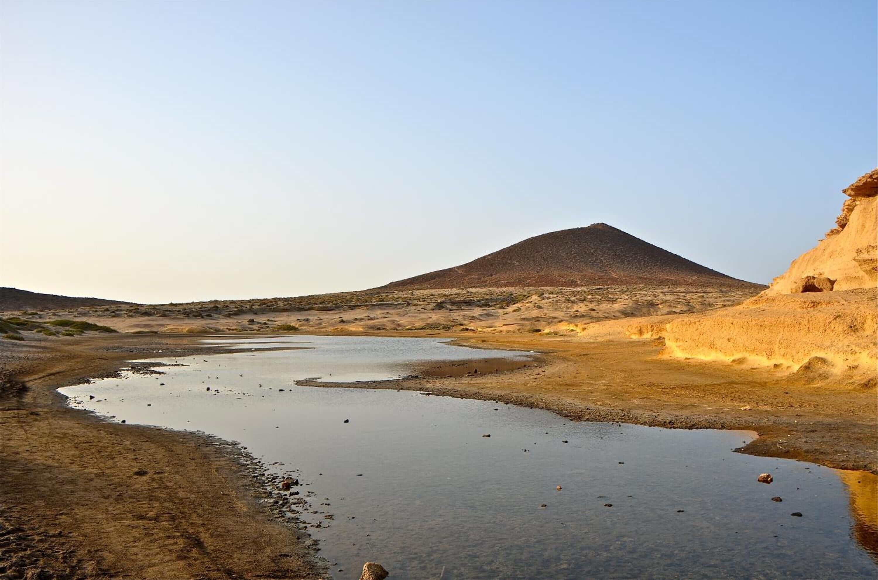 A dry riverbed with a mountain in the background.