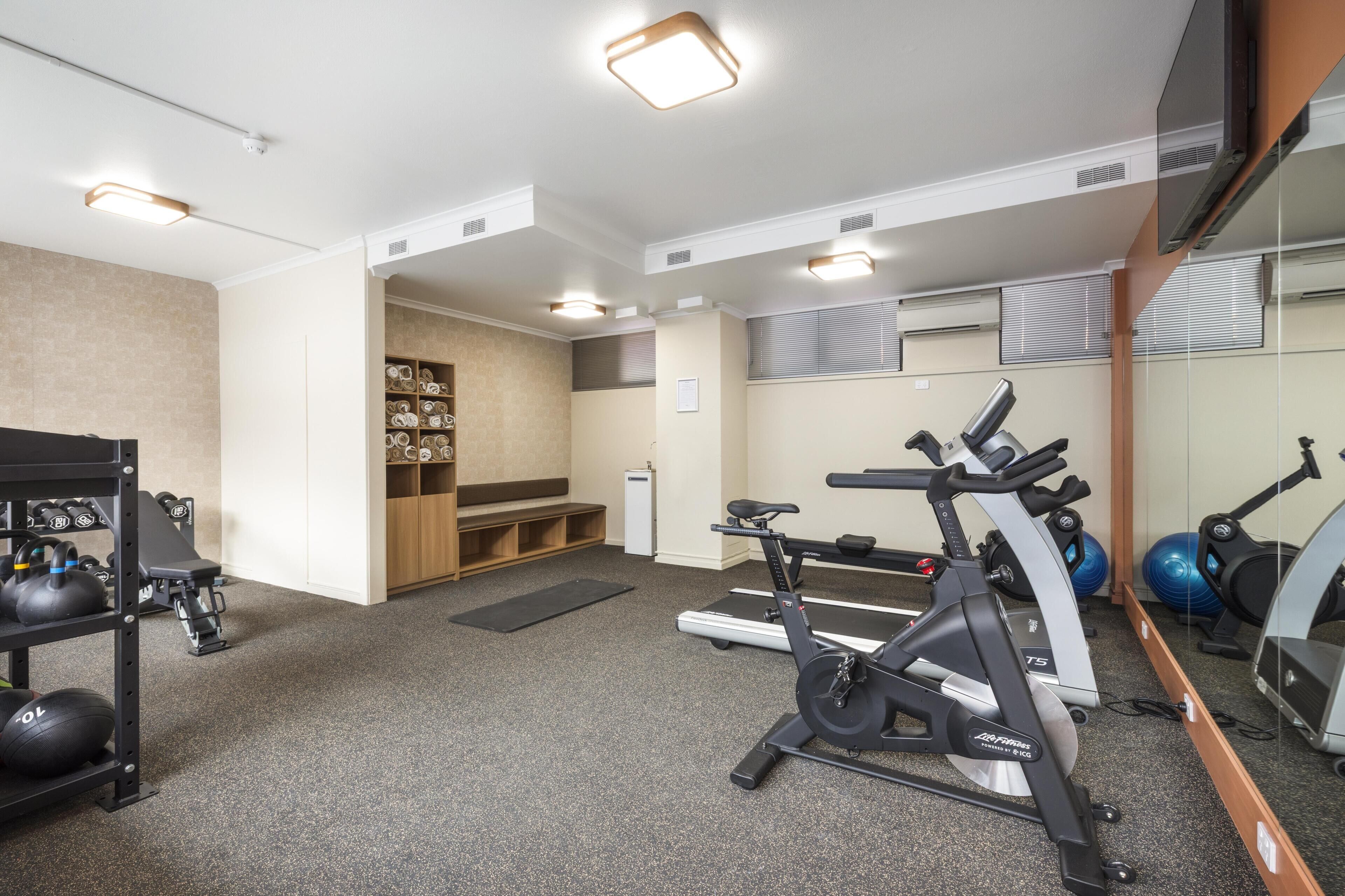 Un gimnasio con equipo de ejercicio, un espejo y una pared con estanterías.