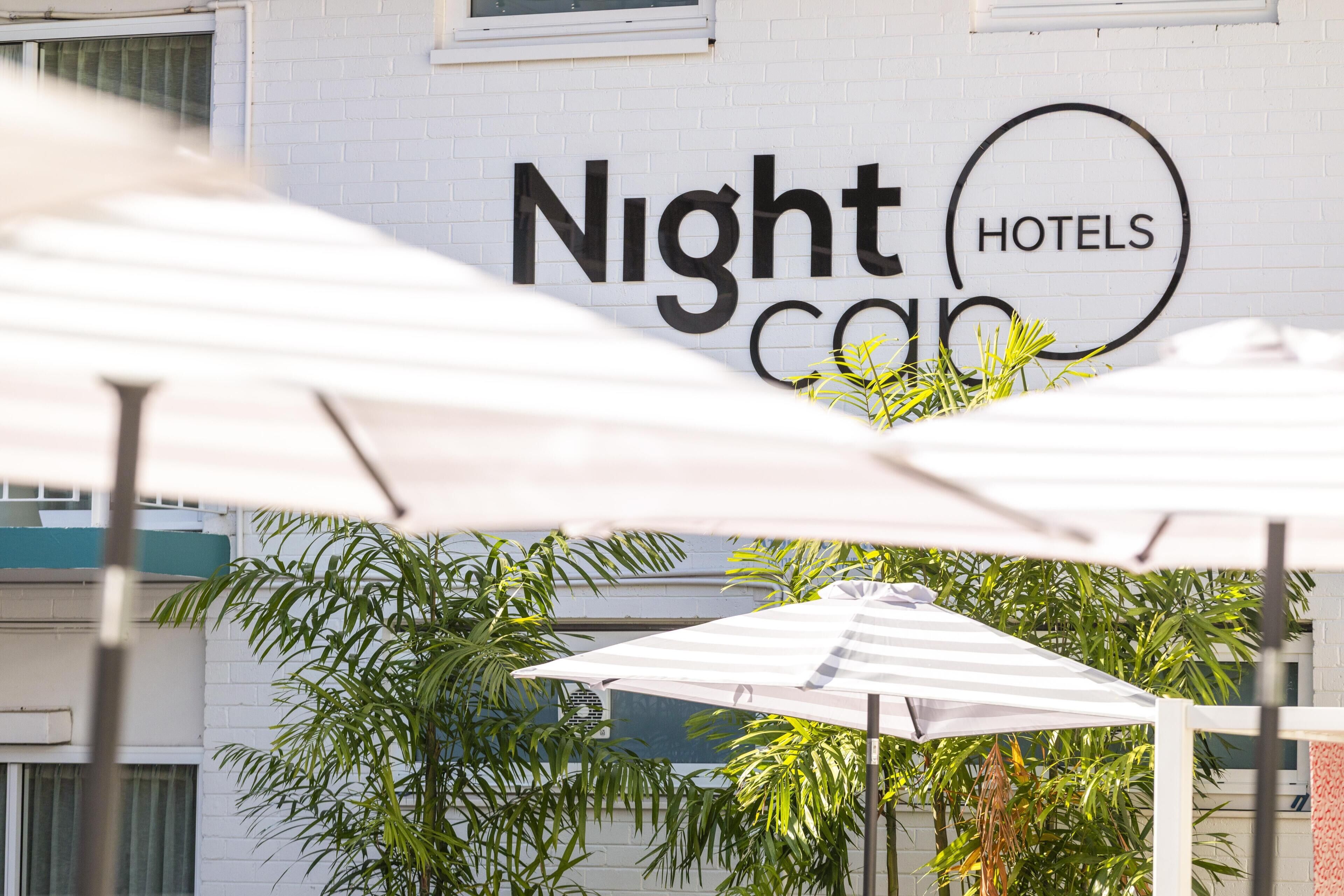 A hotel sign with 'Night Hotels' written on a white brick wall.