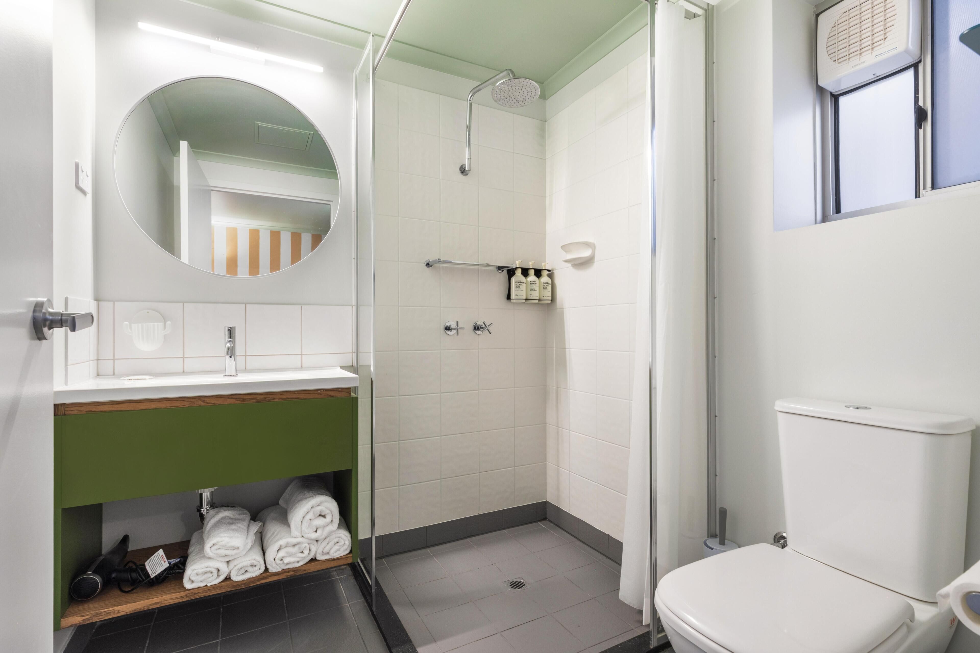 Une salle de bain équipée d’une douche, de toilettes, d’un lavabo et d’un miroir.