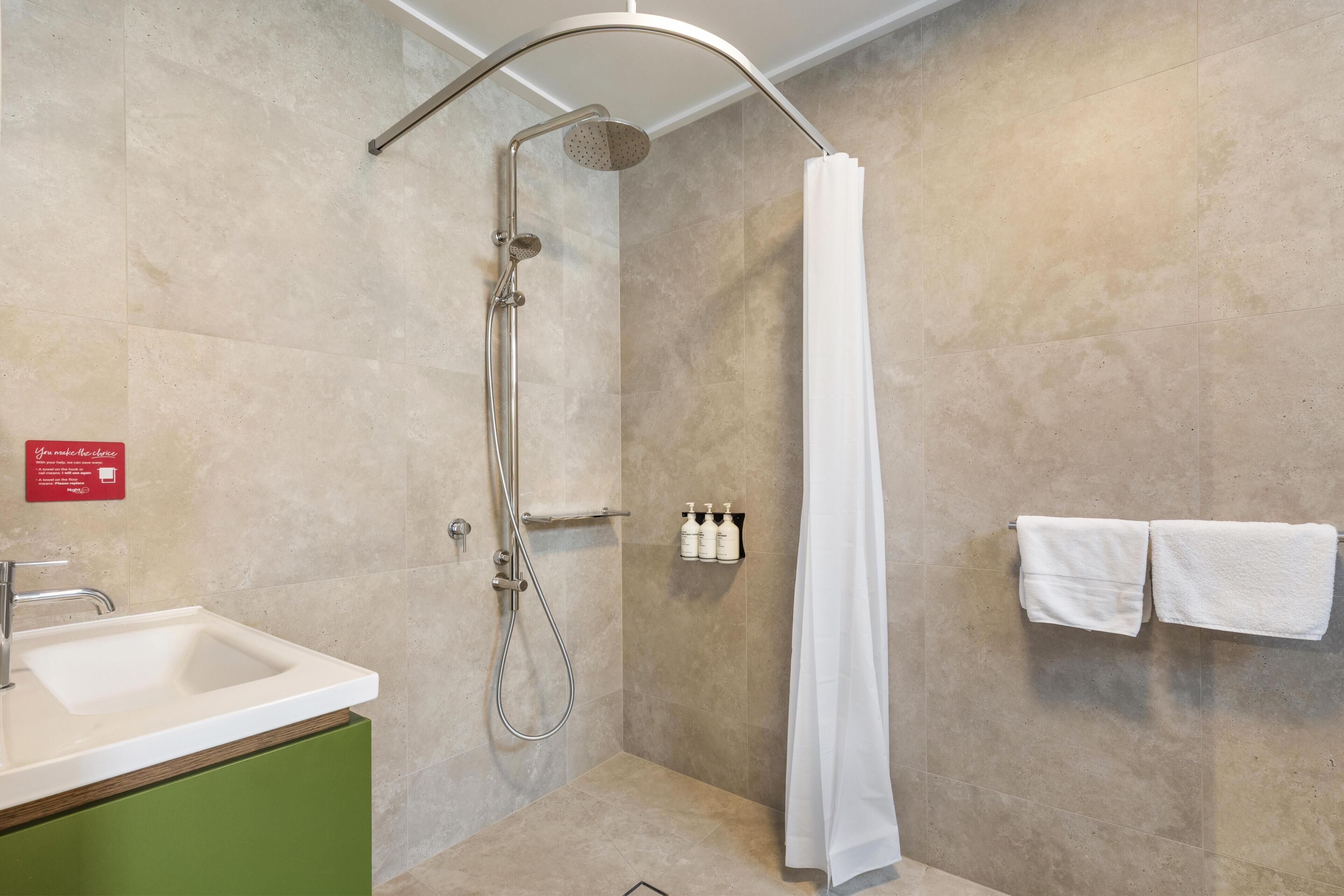 Ein modernes Badezimmer mit Dusche, Waschbecken und Handtuchhalter.