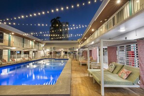Una piscina con sillas de descanso y una zona de estar cubierta.