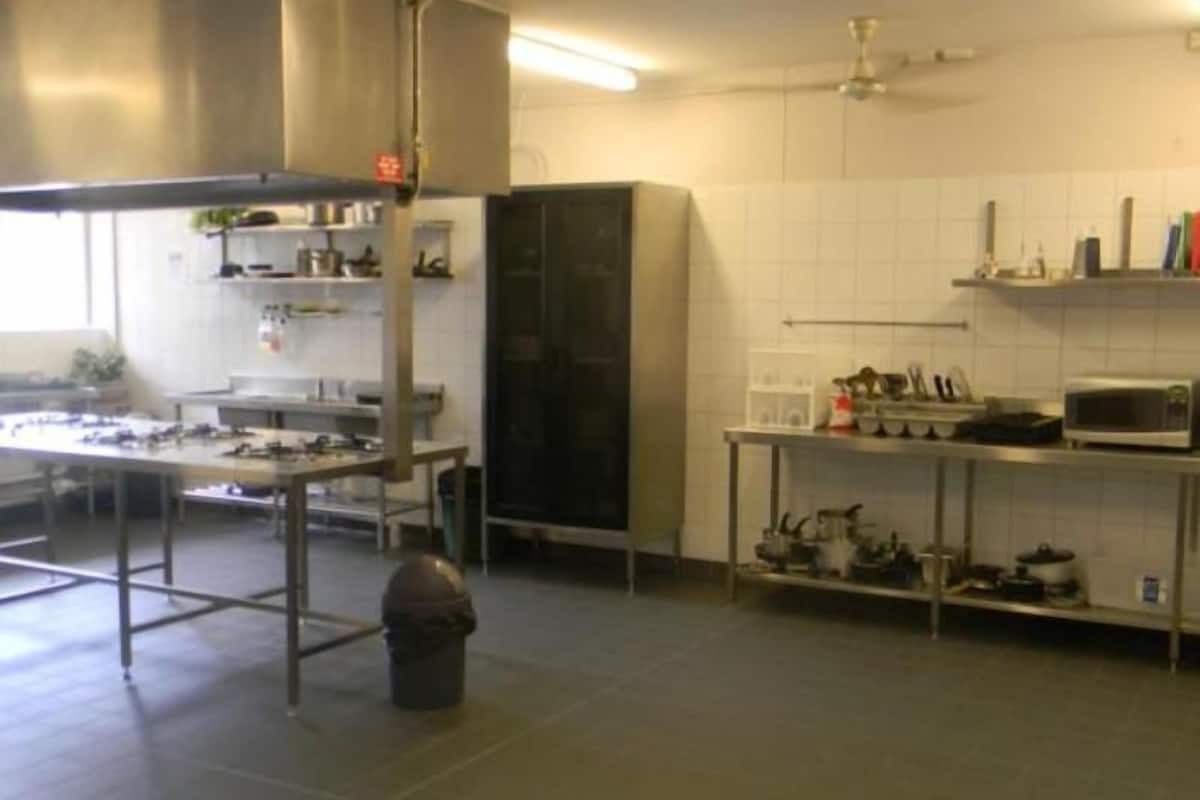 A kitchen with stainless steel appliances, a microwave, and a trash bin.