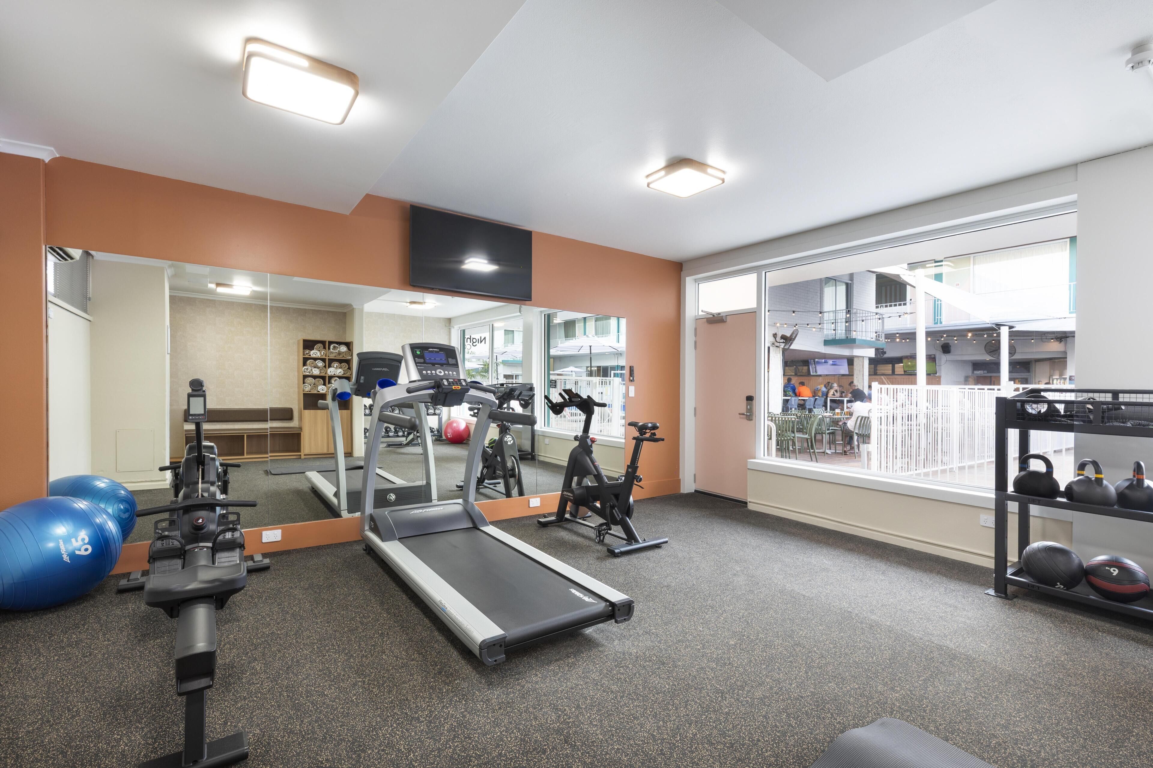 A gym with exercise equipment, a treadmill, and a large window.