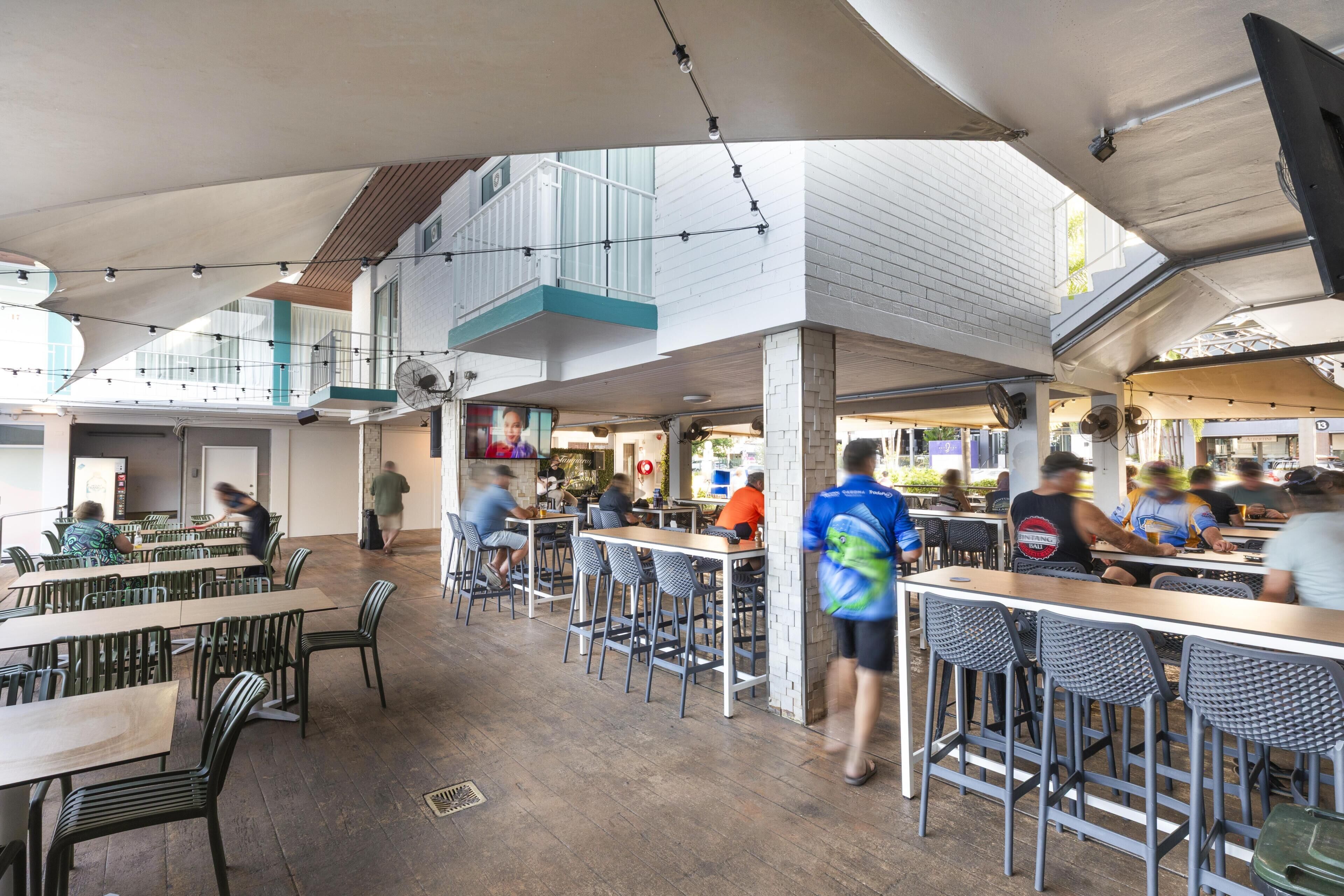 An indoor dining area with high ceilings, multiple dining tables, and chairs.