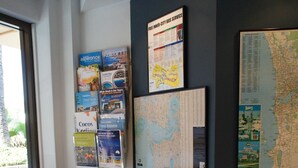 A reception area with a green chair, a wall with travel brochures, a map, and a bulletin board. - City Waters Perth (Perth)