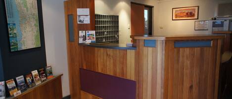 A reception desk with a wooden finish, a map on the wall, and a bulletin board with various notices.