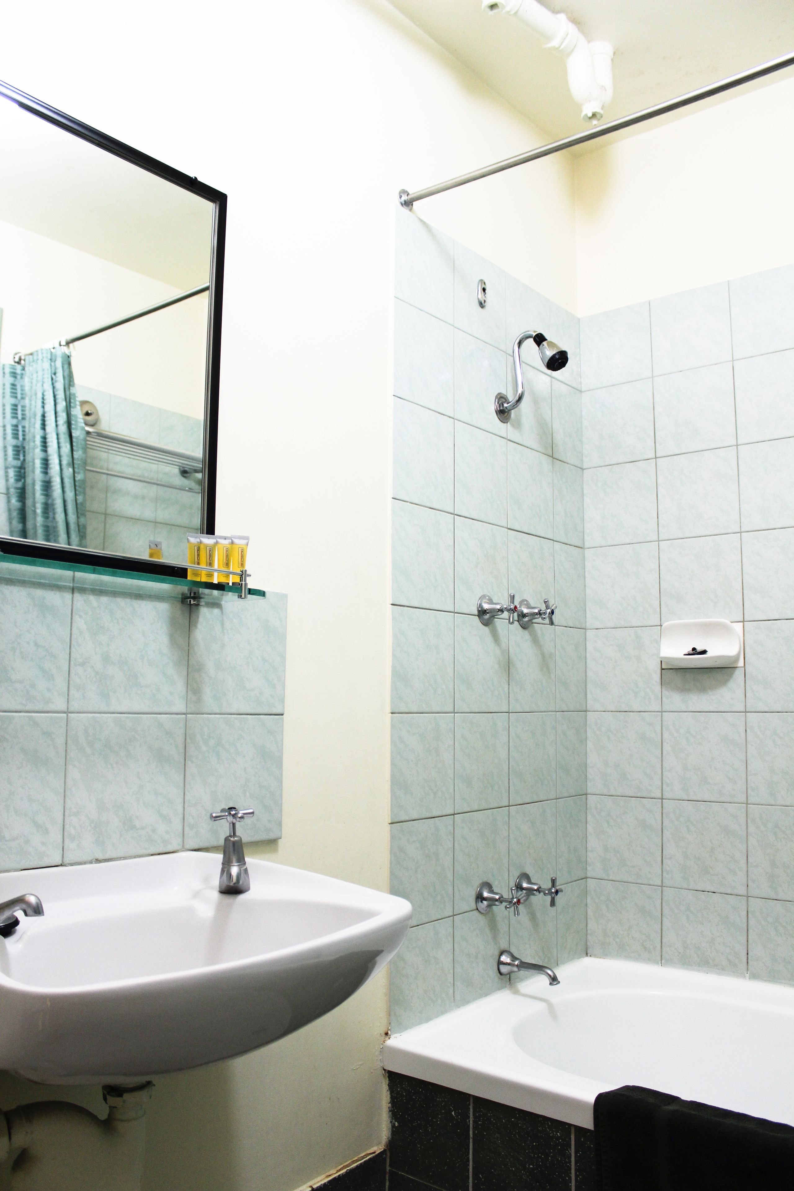 Un baño con lavamanos, espejo y zona de ducha.