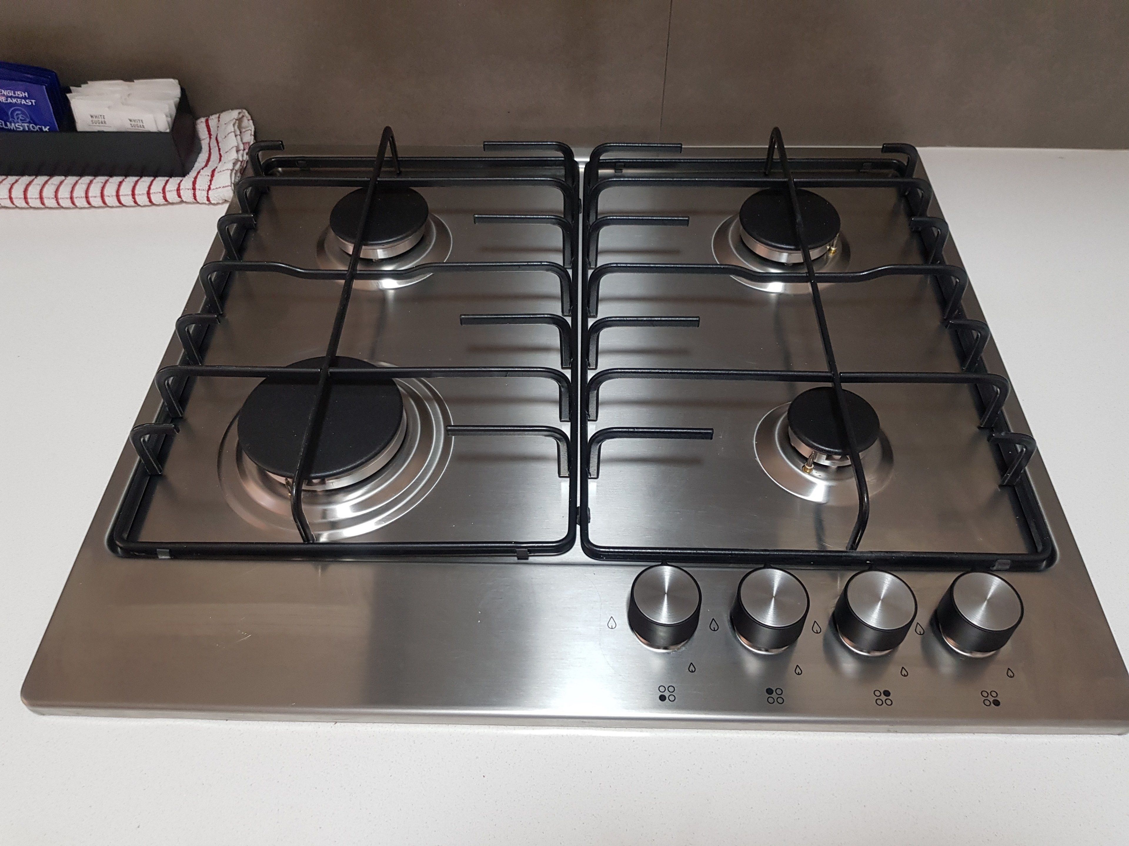 Estufa a gas de cuatro quemadores con perillas de control y acabado de acero inoxidable.