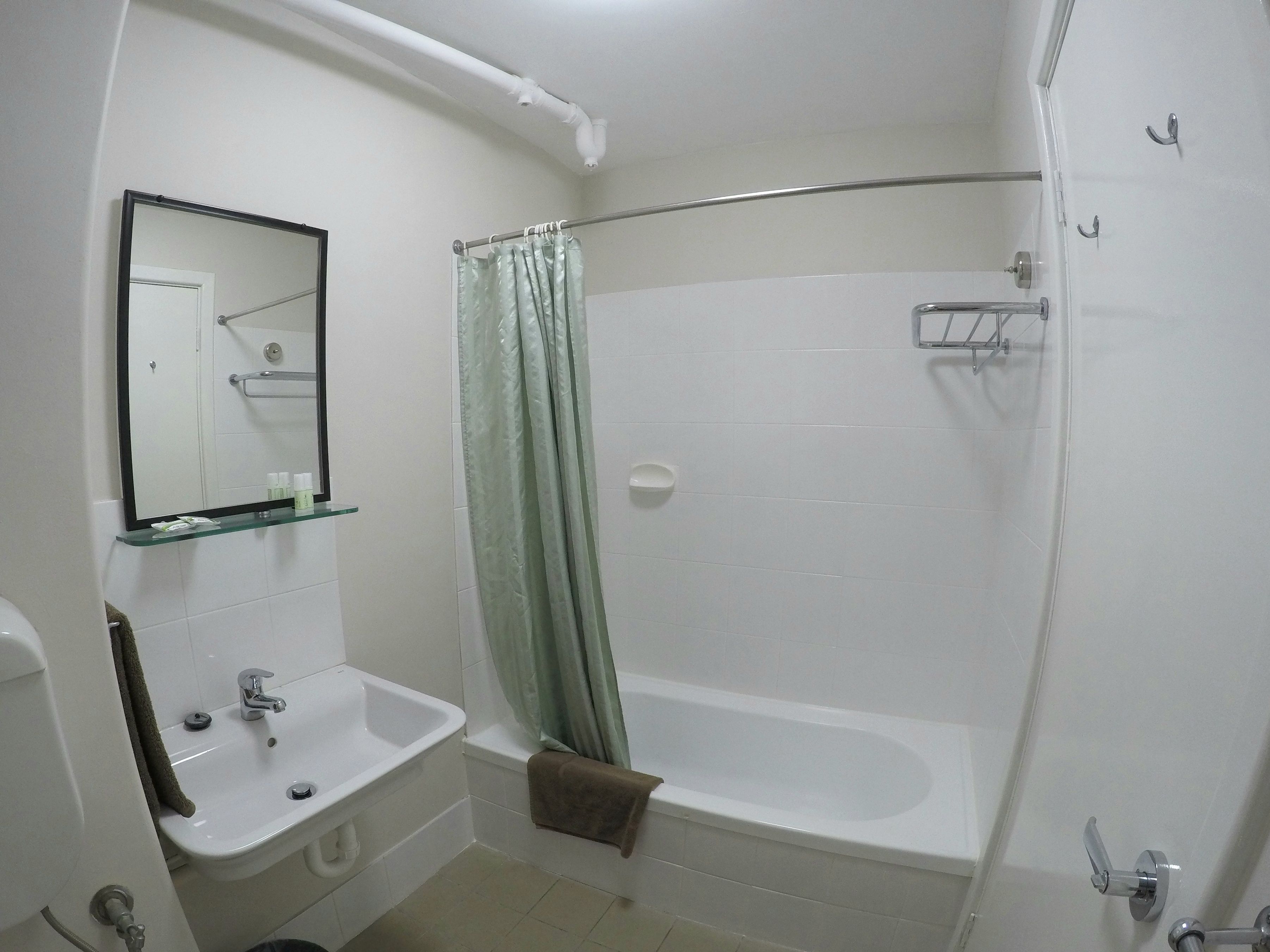 A bathroom with a white sink, mirror, and bathtub.