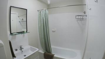 A bathroom with a white sink, mirror, and bathtub.