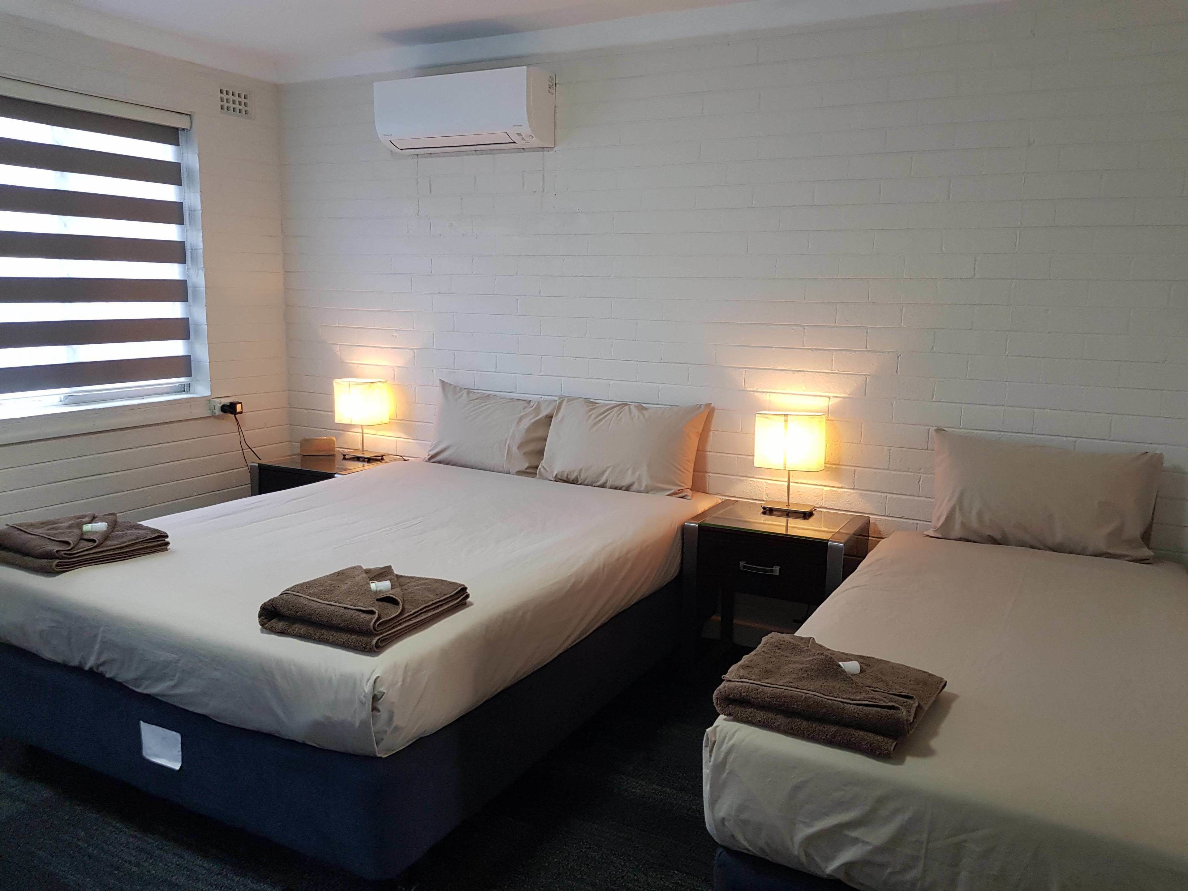 Une chambre d’hôtel avec deux lits, du linge de lit blanc et des lampes de chevet.