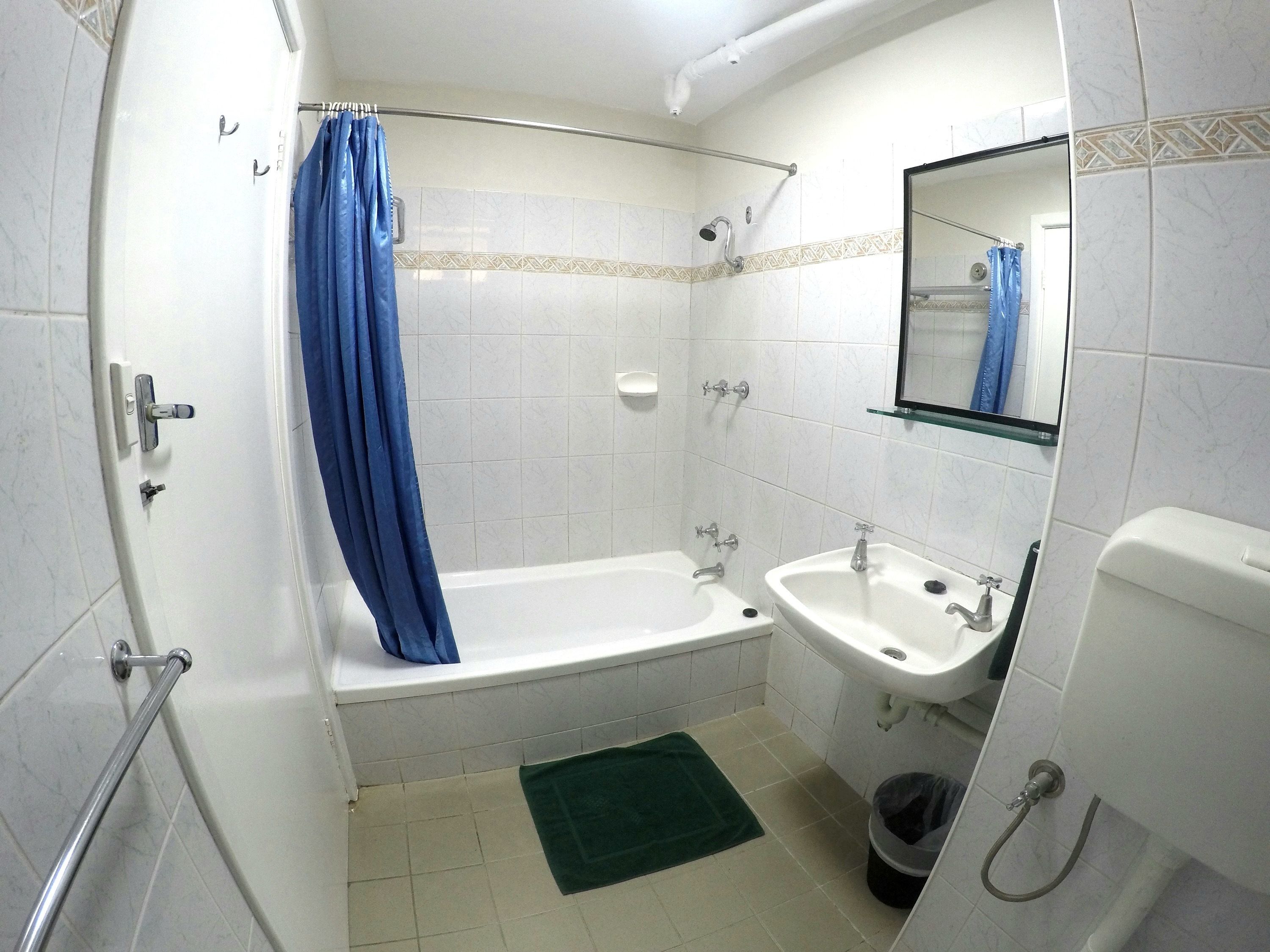 A bathroom with a bathtub, a sink, a mirror, and a shower curtain.