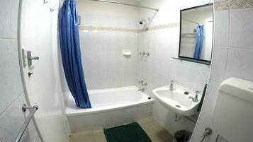 A bathroom with a bathtub, a sink, a mirror, and a shower curtain.