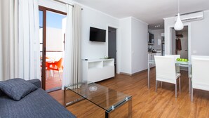A modern living room with a glass coffee table, a sofa, and a dining area with a table and chairs. - Apartamentos Villa Florida (Antigua)