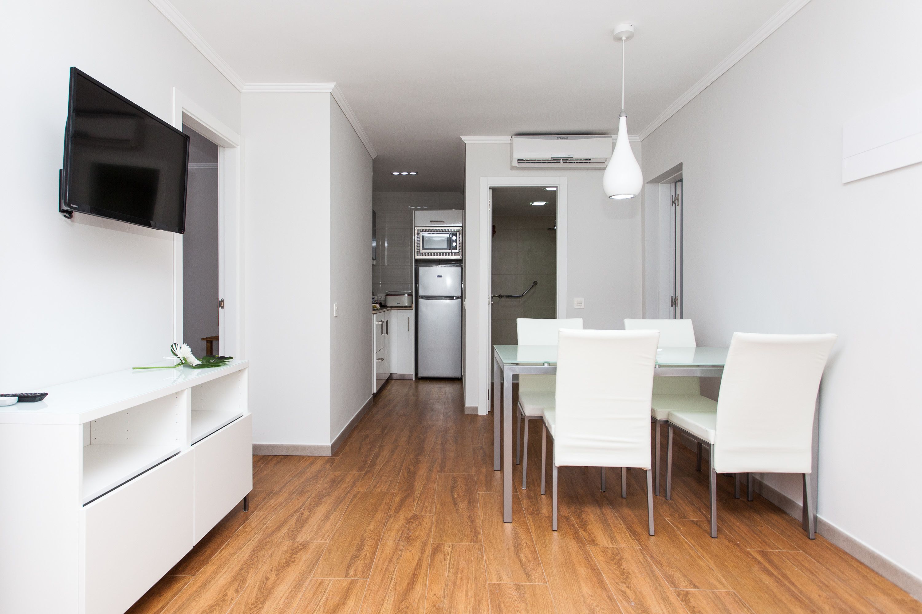 A modern kitchen with white cabinetry, a built-in microwave, and a stainless steel refrigerator.