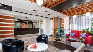 A modern hotel lobby with a reception desk, leather seating, a red sofa, and a patterned rug. - Apartamentos Villa Florida (Antigua)