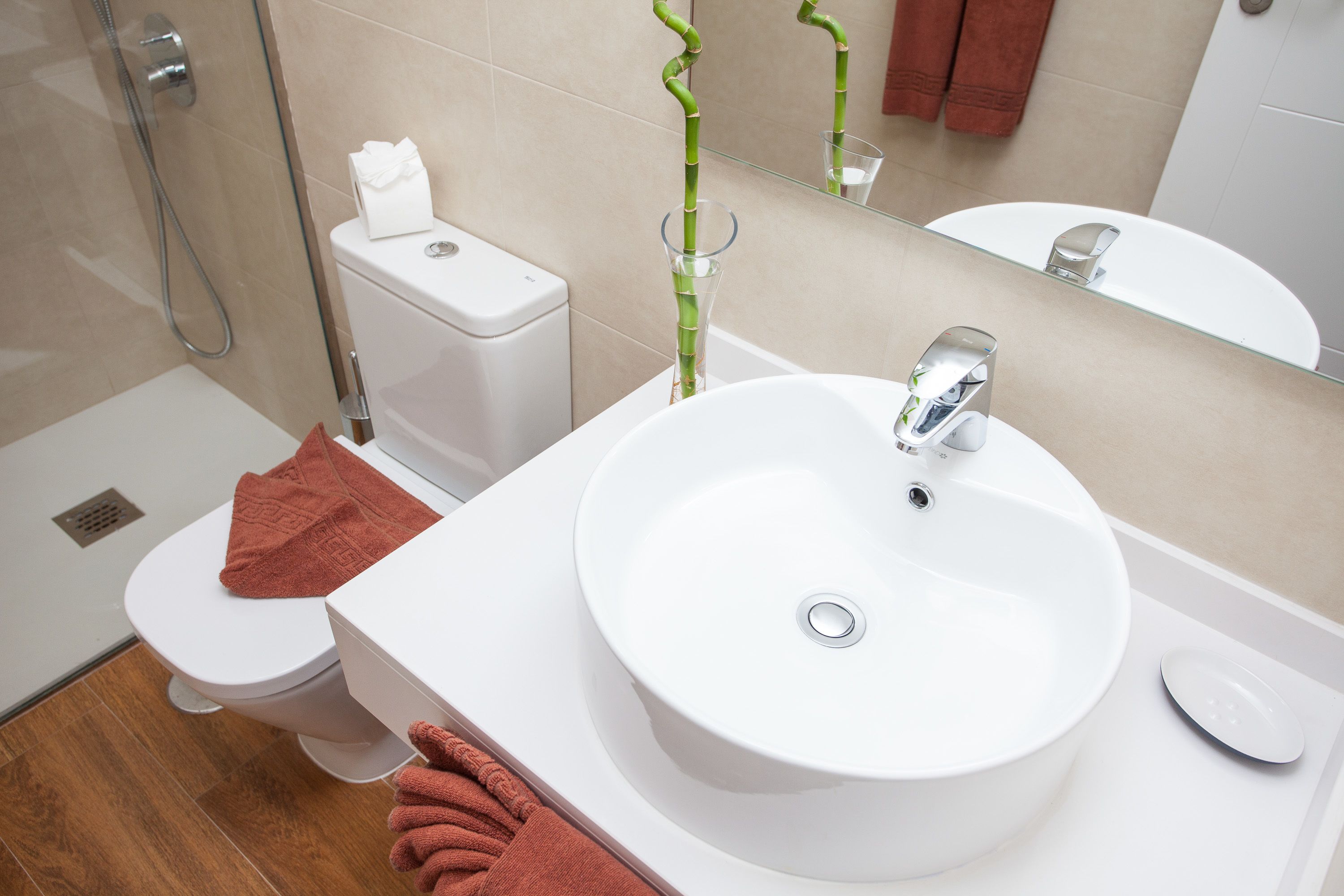 A modern bathroom with a white sink, toilet, and shower.