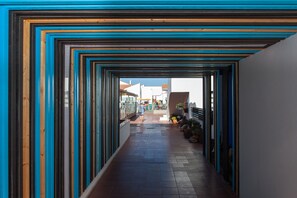 A corridor with a repeating pattern of wooden and blue panels, leading to a building with a glass facade. - Apartamentos Villa Florida (Antigua)