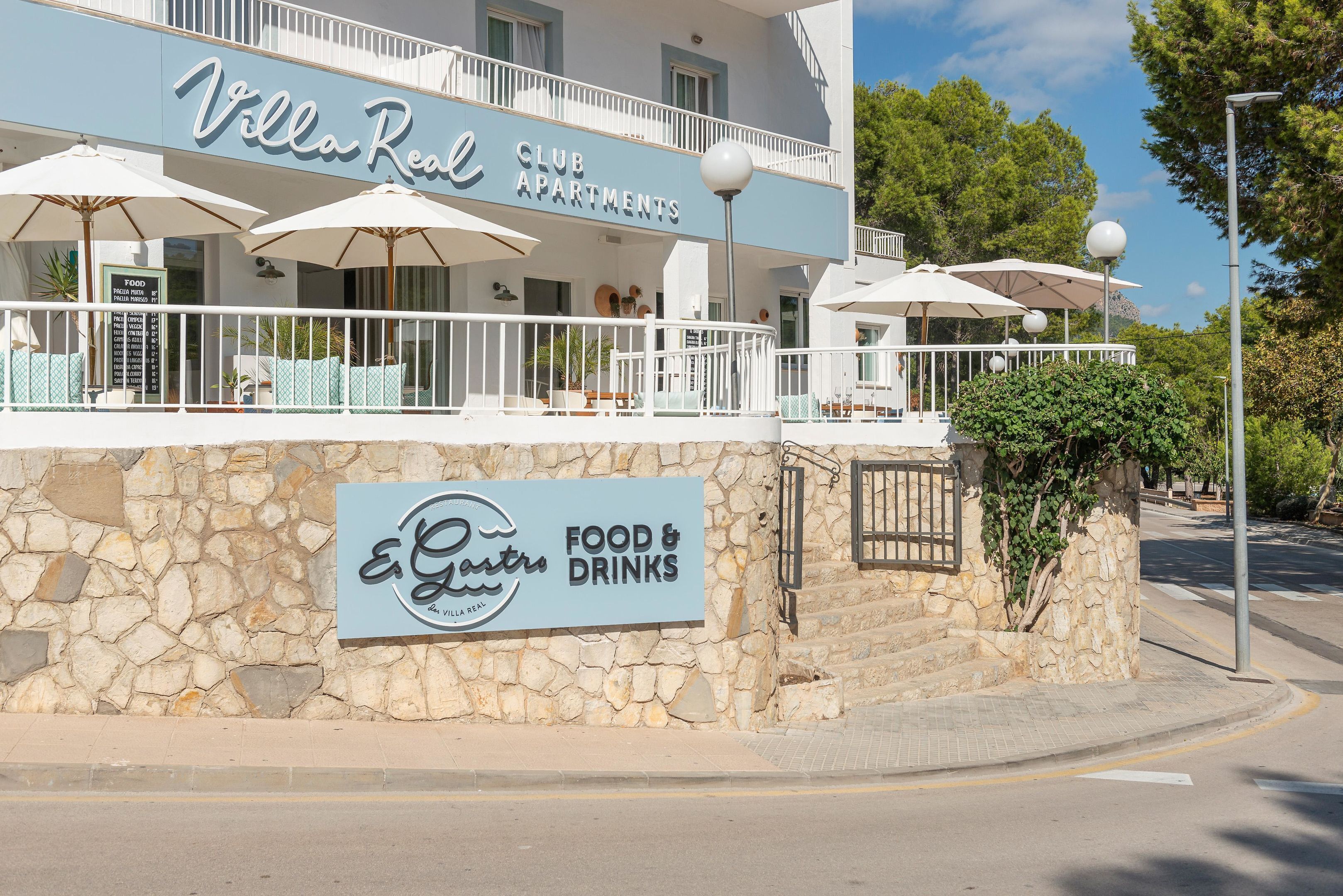 Villa Real Club Apartments with outdoor seating and a sign for E.Gastro Food & Drinks.