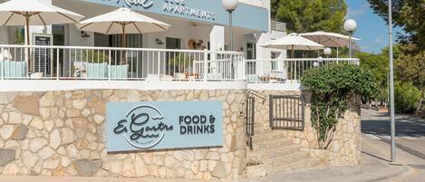 Villa Real Club Apartments with outdoor seating and a sign for E.Gastro Food & Drinks.