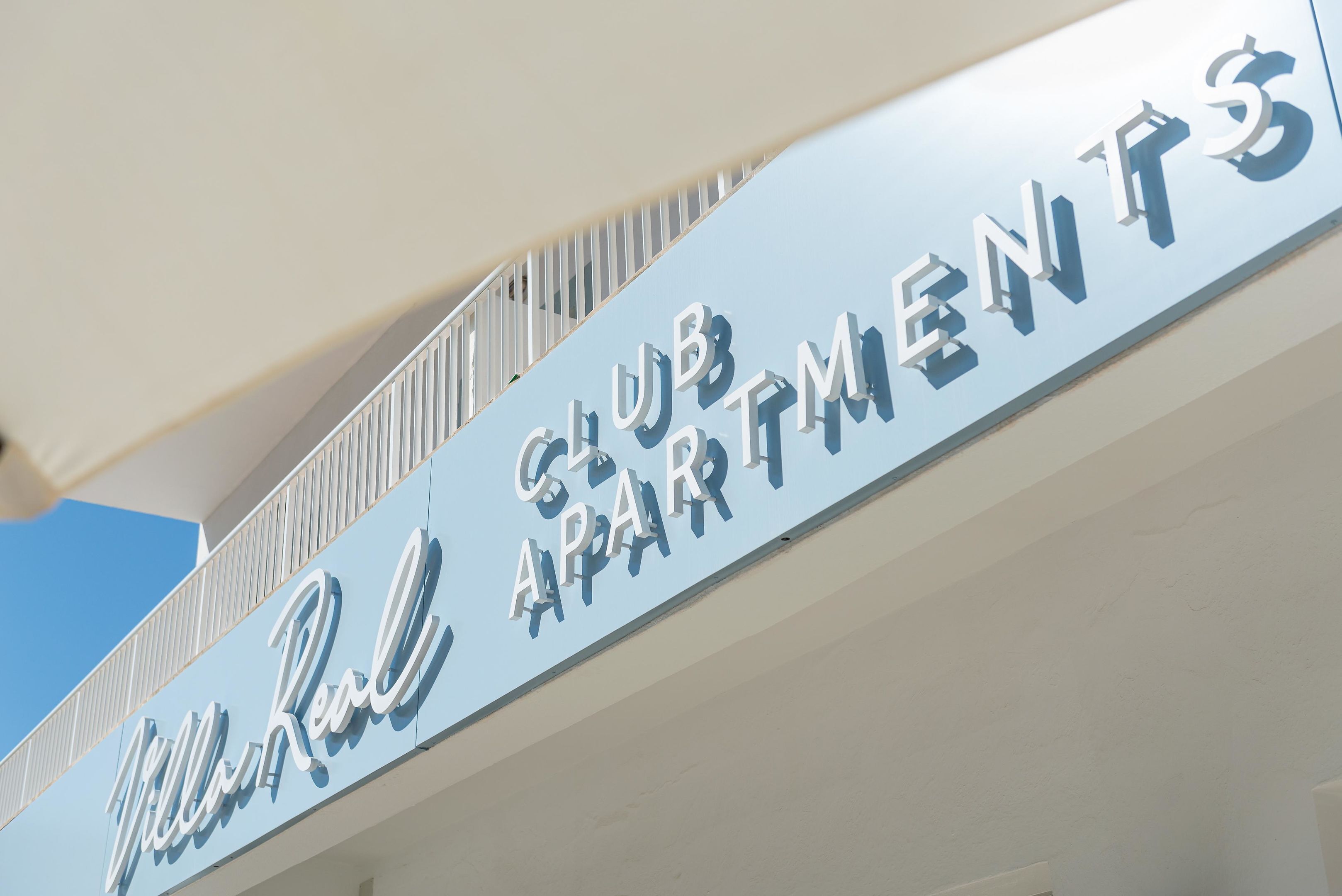 Une enseigne indiquant « Club Apartments » avec une balustrade de balcon.