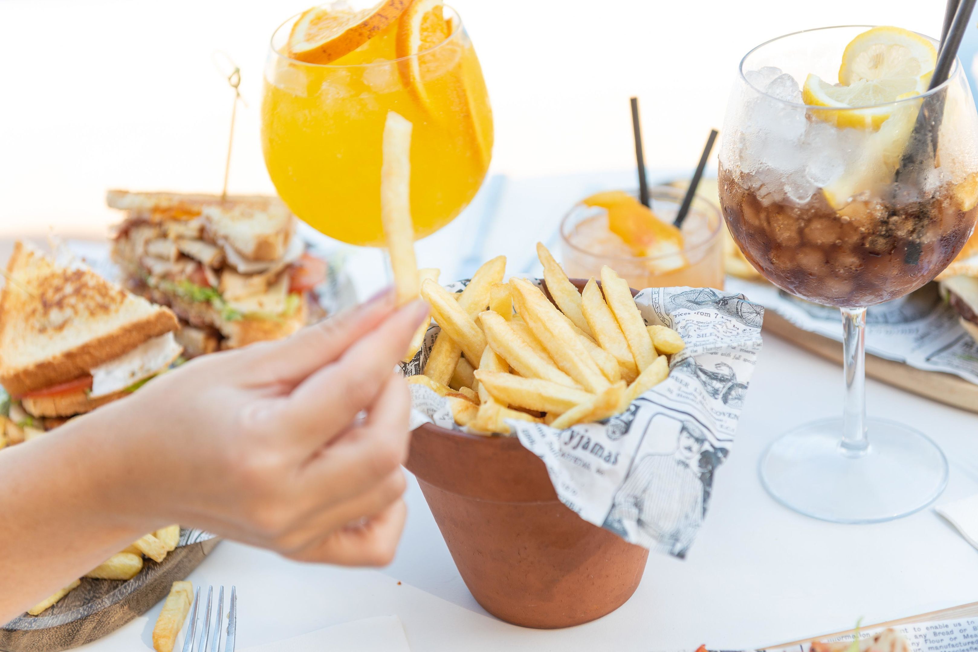 Una comida con sándwich, papas fritas, una bebida y un vaso de té helado.