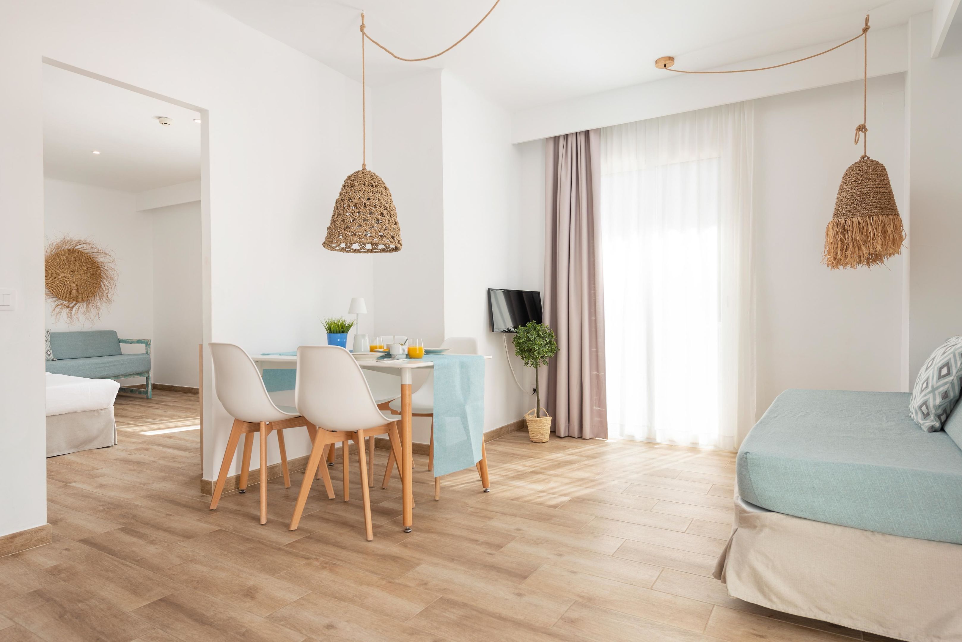 Un salon moderne comprenant un coin repas, un canapé, un téléviseur et un luminaire suspendu.