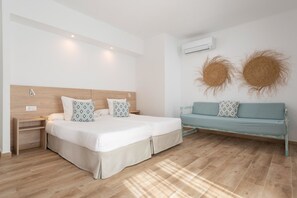 Une chambre à coucher avec un lit double, des tables de chevet, un canapé et deux unités de climatisation fixées au mur.